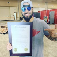 a man holding up a framed certificate with a smile on his face
